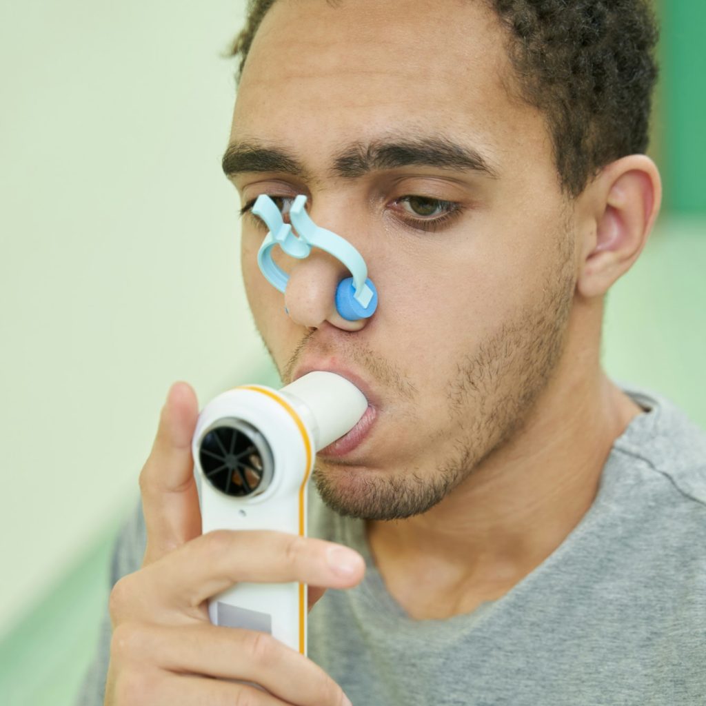 Person taking lung finctionality test with spirometry device
