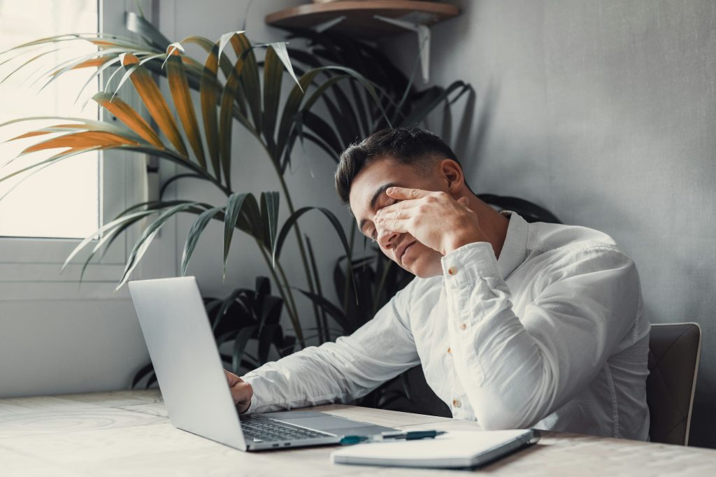 Stressed tired man in pain having strong terrible headache attack after computer